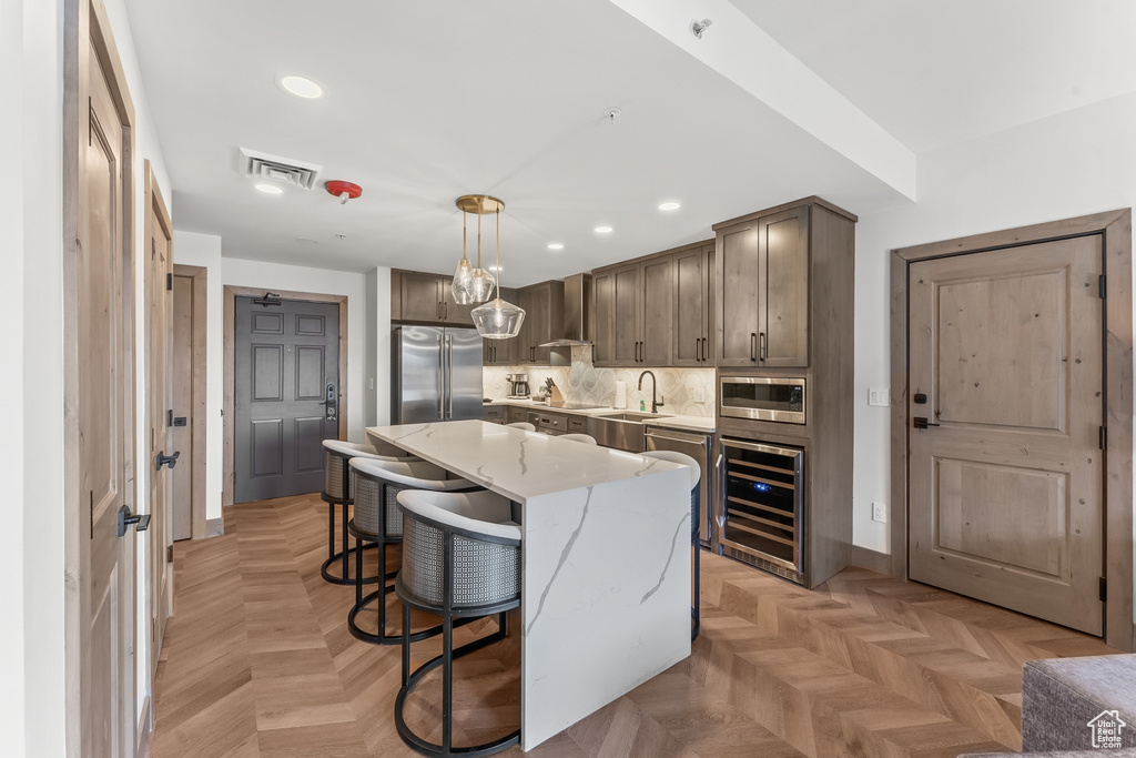 Kitchen with appliances with stainless steel finishes, a kitchen island, light parquet flooring, and wine cooler