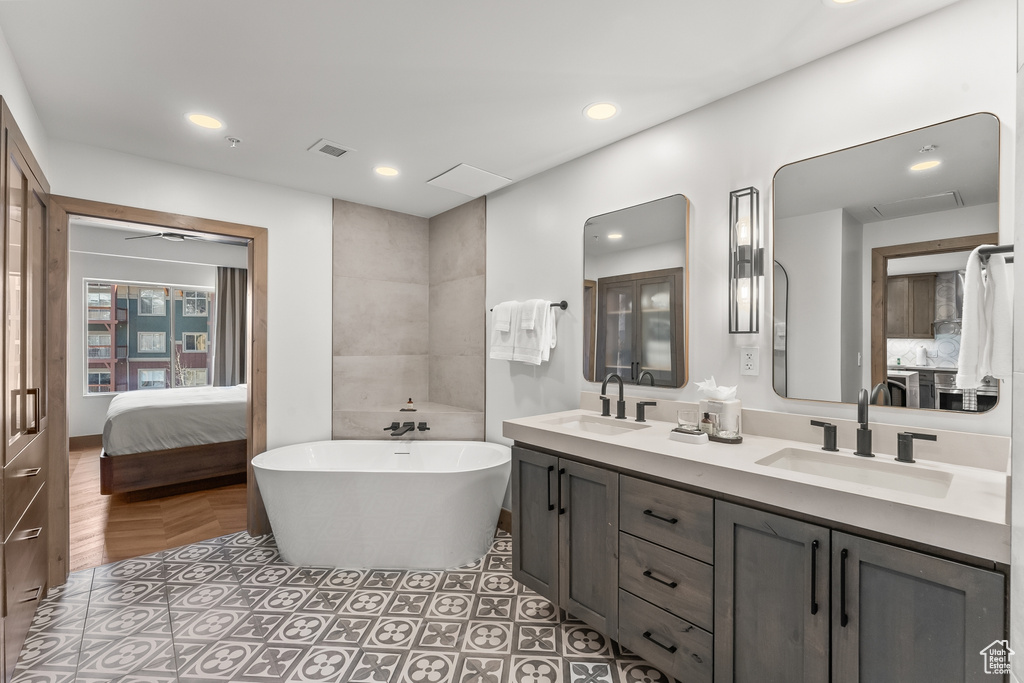 Bathroom with vanity with extensive cabinet space, double sink, a bathtub, and tile flooring