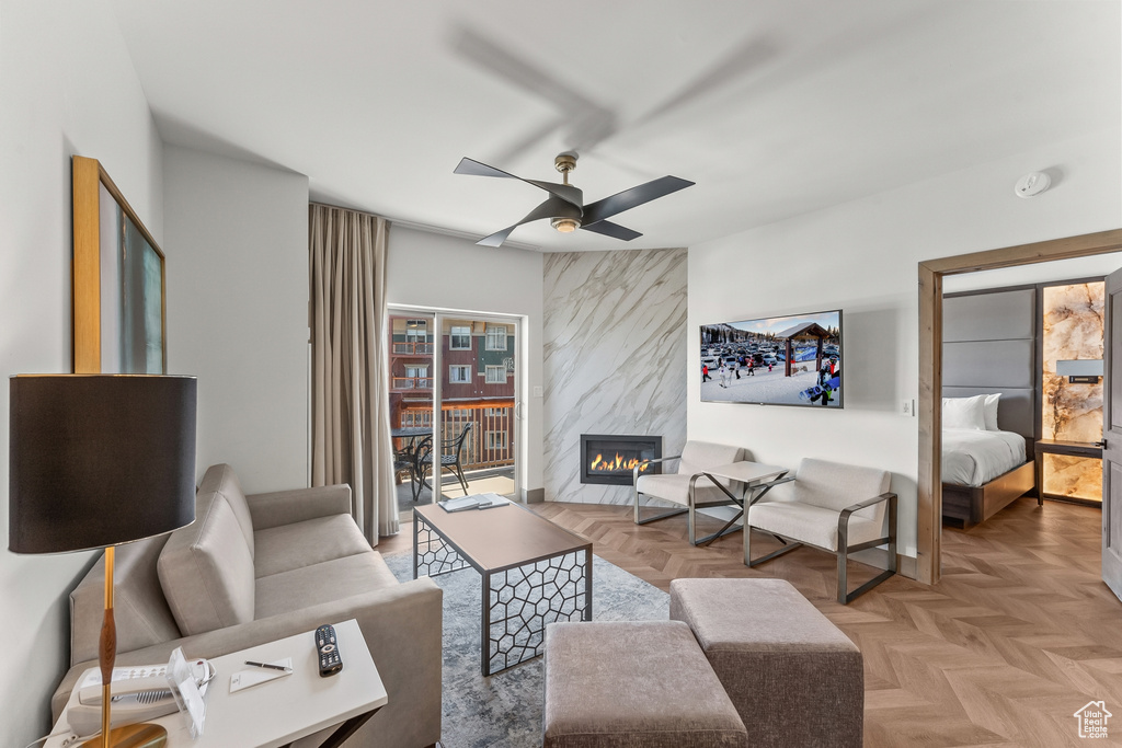 Living room featuring ceiling fan, light parquet flooring, and a large fireplace
