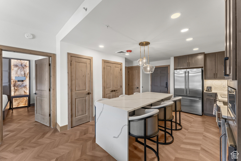 Kitchen featuring light stone counters, built in fridge, light parquet floors, and a center island