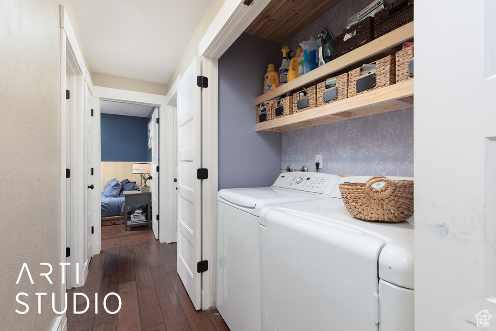 Clothes washing area with washer and clothes dryer and dark hardwood / wood-style flooring