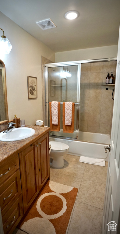 Full bathroom with toilet, combined bath / shower with glass door, vanity, and tile flooring
