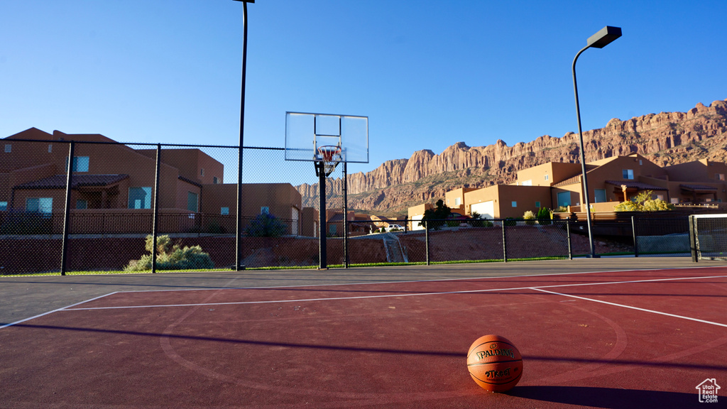 View of tennis court with a mountain view and basketball hoop