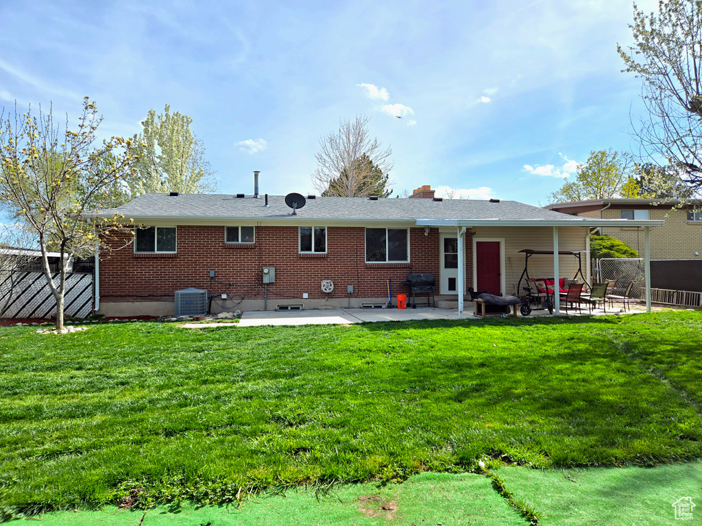 Rear view of property featuring central AC, a yard, and a patio area