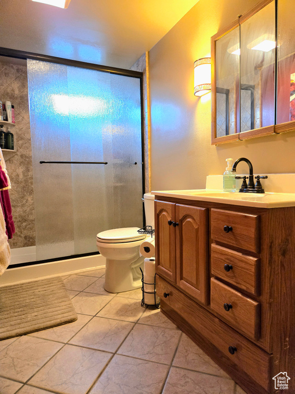 Bathroom featuring an enclosed shower, toilet, tile flooring, and vanity