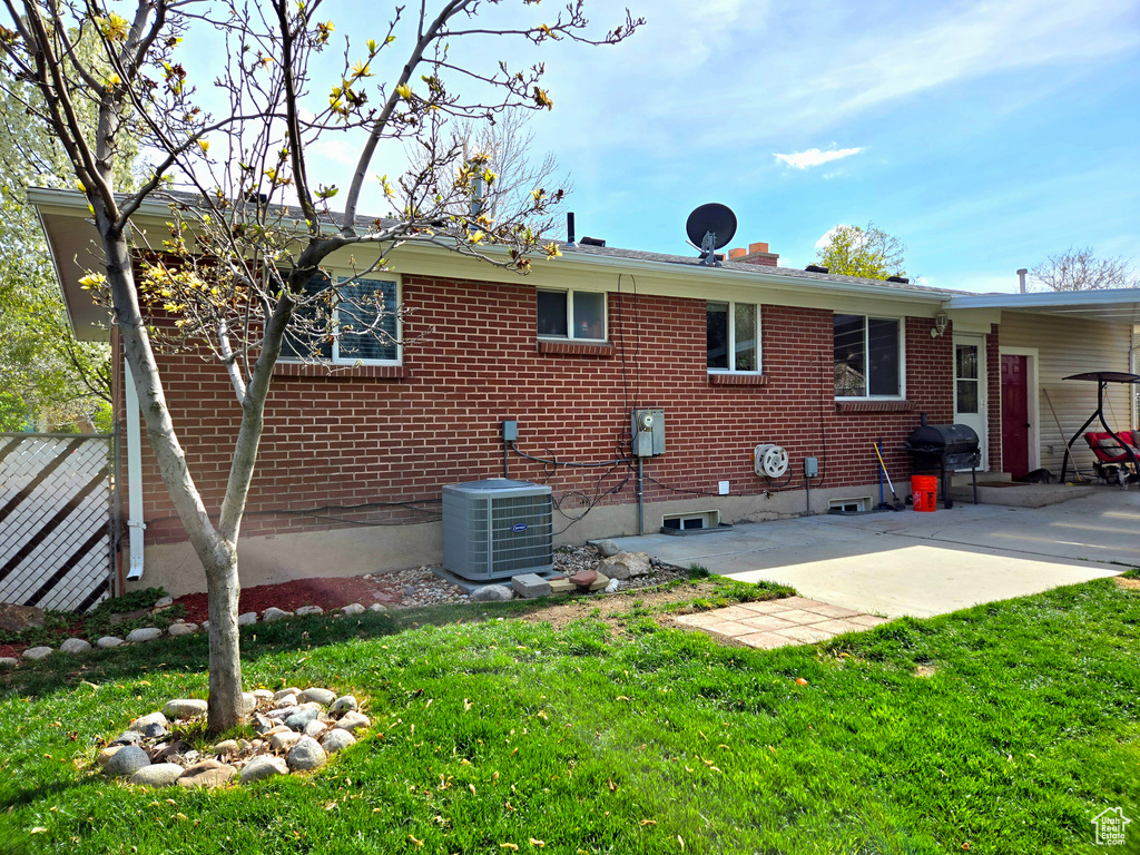 Rear view of property with a patio, a yard, and central air condition unit
