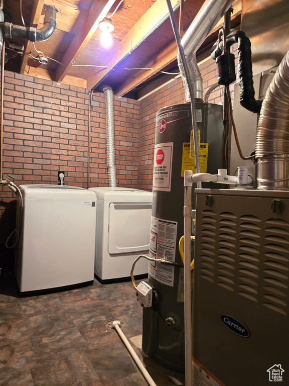 Laundry area featuring brick wall, wood ceiling, water heater, and washer and dryer