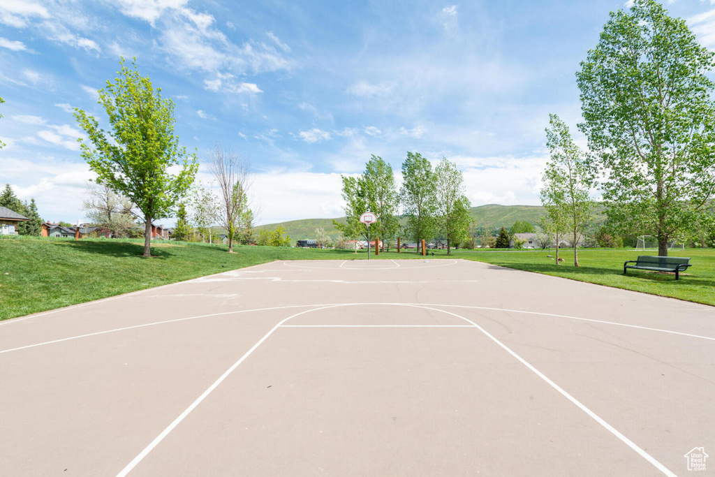 View of basketball court featuring a mountain view and a yard