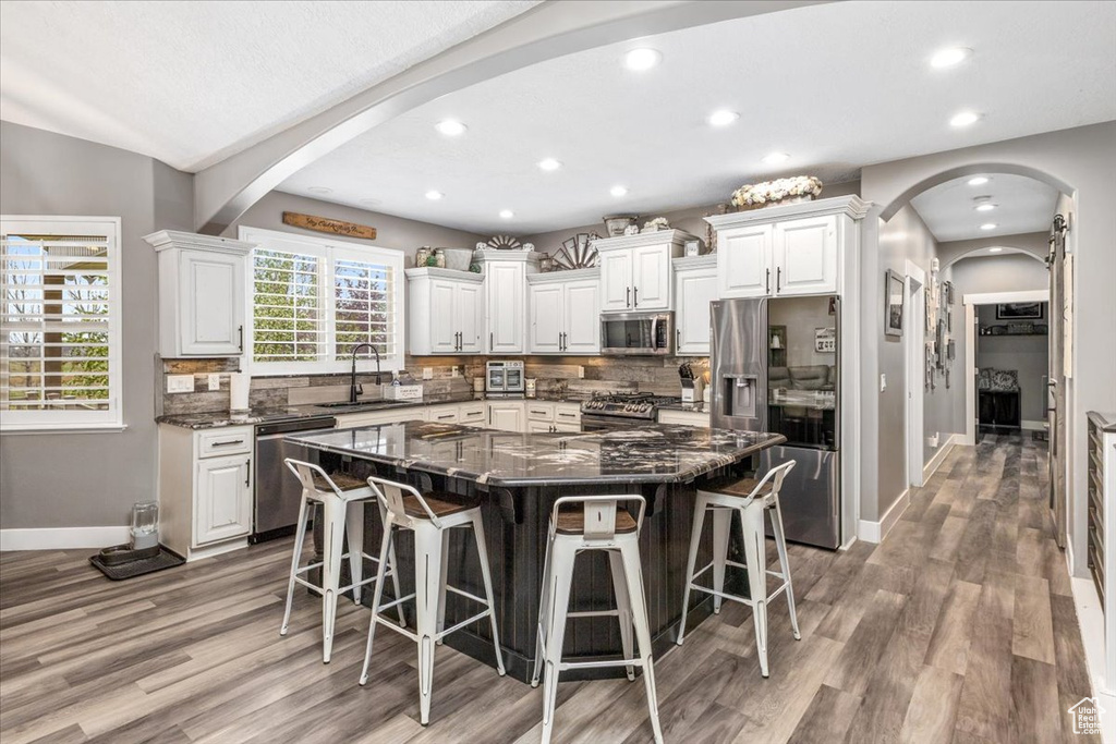 Kitchen featuring appliances with stainless steel finishes, light hardwood / wood-style flooring, a breakfast bar area, sink, and a center island