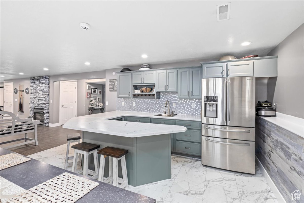 Kitchen with sink, tasteful backsplash, gray cabinets, stainless steel fridge with ice dispenser, and a kitchen breakfast bar