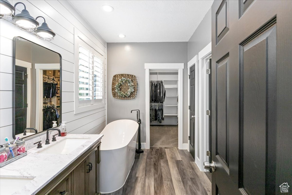 Bathroom featuring a tub, dual bowl vanity, and hardwood / wood-style flooring