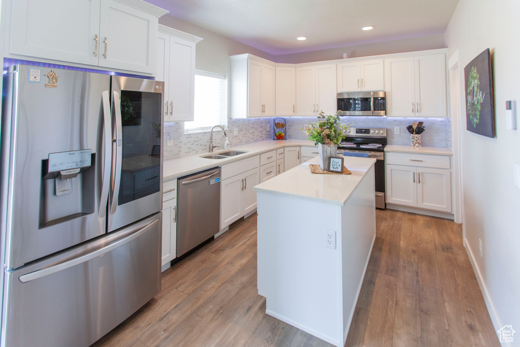 Kitchen with sink, appliances with stainless steel finishes, backsplash, and wood-type flooring