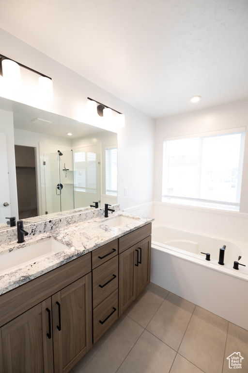 Bathroom featuring tile flooring, oversized vanity, separate shower and tub, and dual sinks
