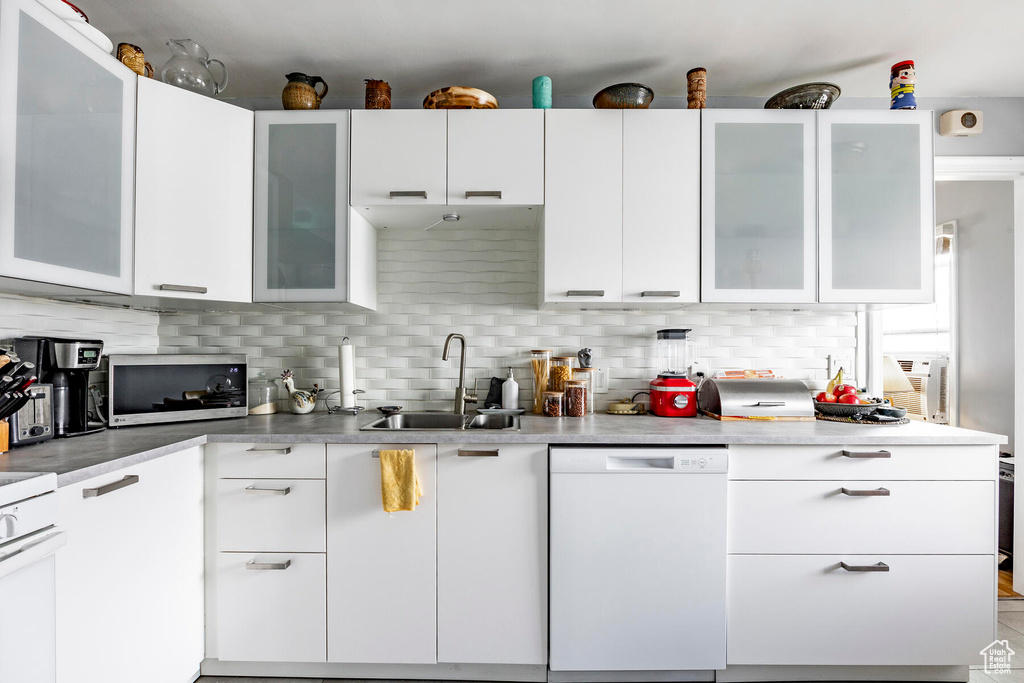 Kitchen featuring white cabinets, sink, backsplash, and dishwasher