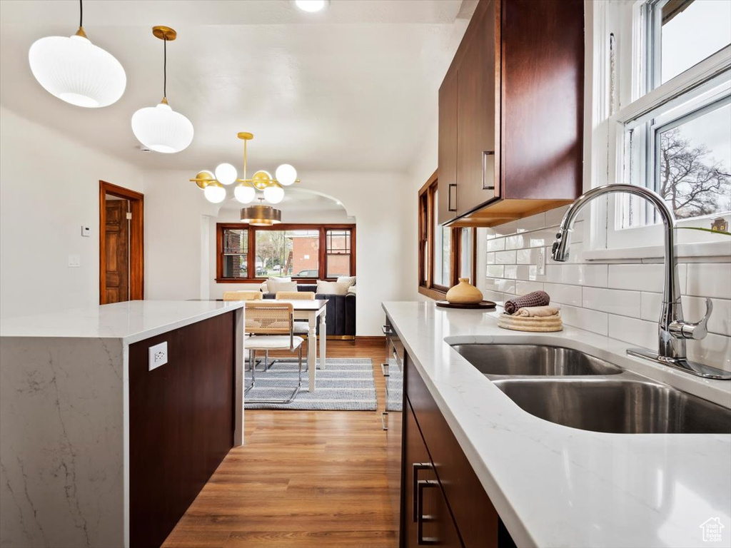 Kitchen with decorative light fixtures, backsplash, a healthy amount of sunlight, and light wood-type flooring