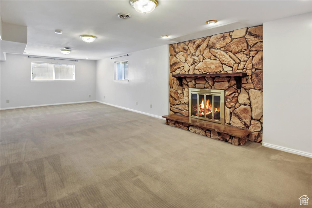 Unfurnished living room with carpet flooring and a stone fireplace