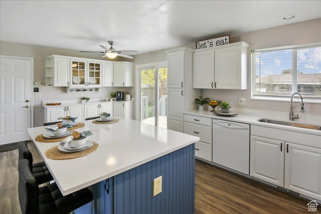 Kitchen with white cabinets, dark hardwood / wood-style floors, white dishwasher, a breakfast bar area, and ceiling fan