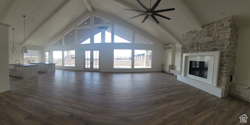 Unfurnished living room with high vaulted ceiling, beam ceiling, and dark wood-type flooring