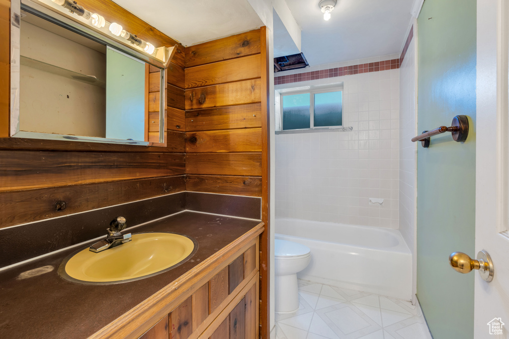 Full bathroom with vanity with extensive cabinet space, tiled shower / bath, toilet, and tile floors