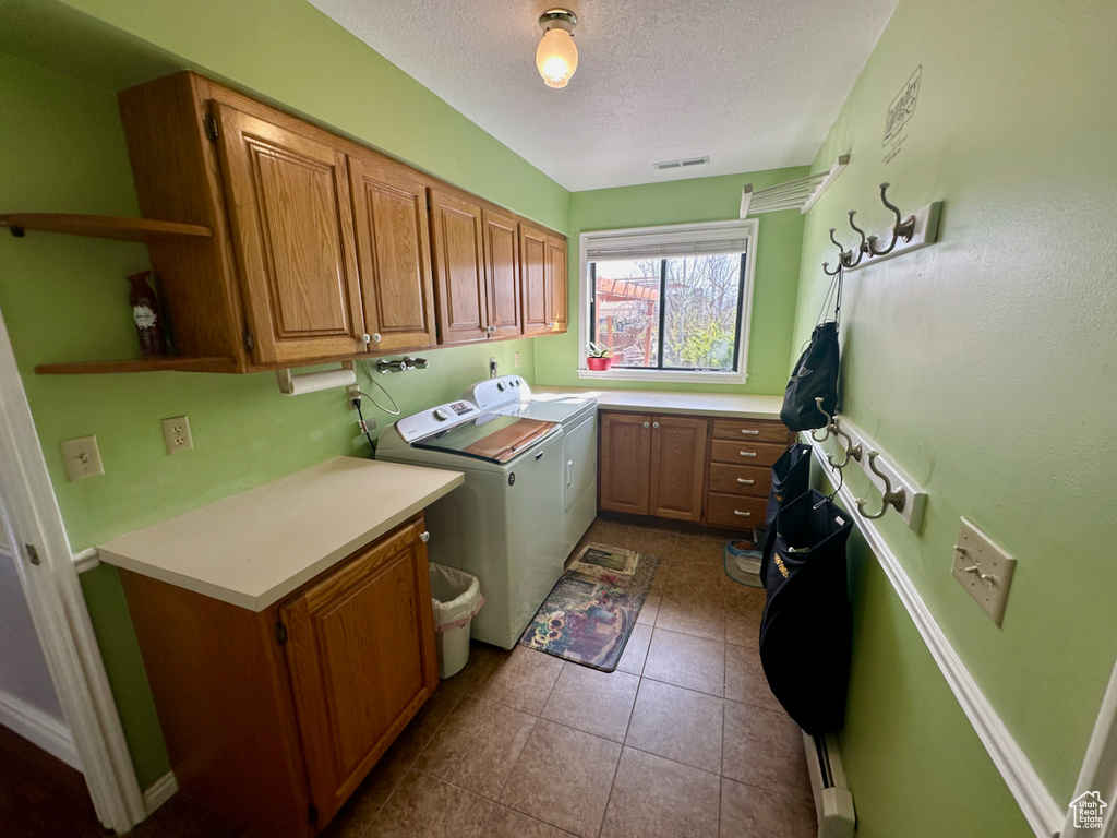 Laundry area featuring independent washer and dryer, dark tile flooring, cabinets, and a textured ceiling