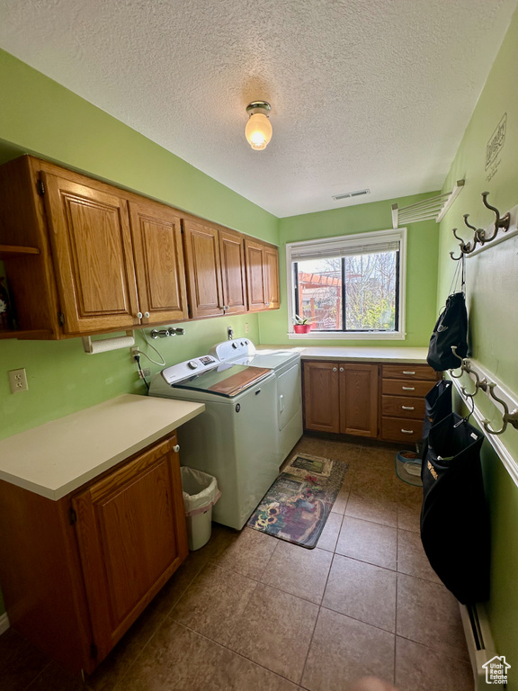 Laundry area featuring dark tile floors, independent washer and dryer, cabinets, and a textured ceiling