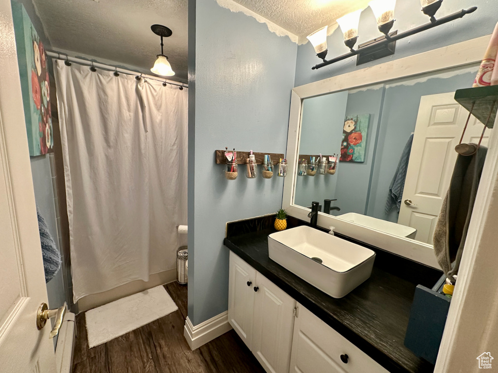 Bathroom featuring a textured ceiling, vanity, and hardwood / wood-style floors