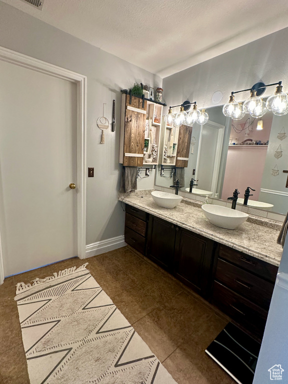 Bathroom featuring tile floors, a textured ceiling, and double sink vanity