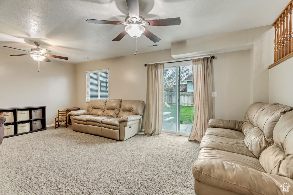 Living room with light carpet, ceiling fan, and a wealth of natural light