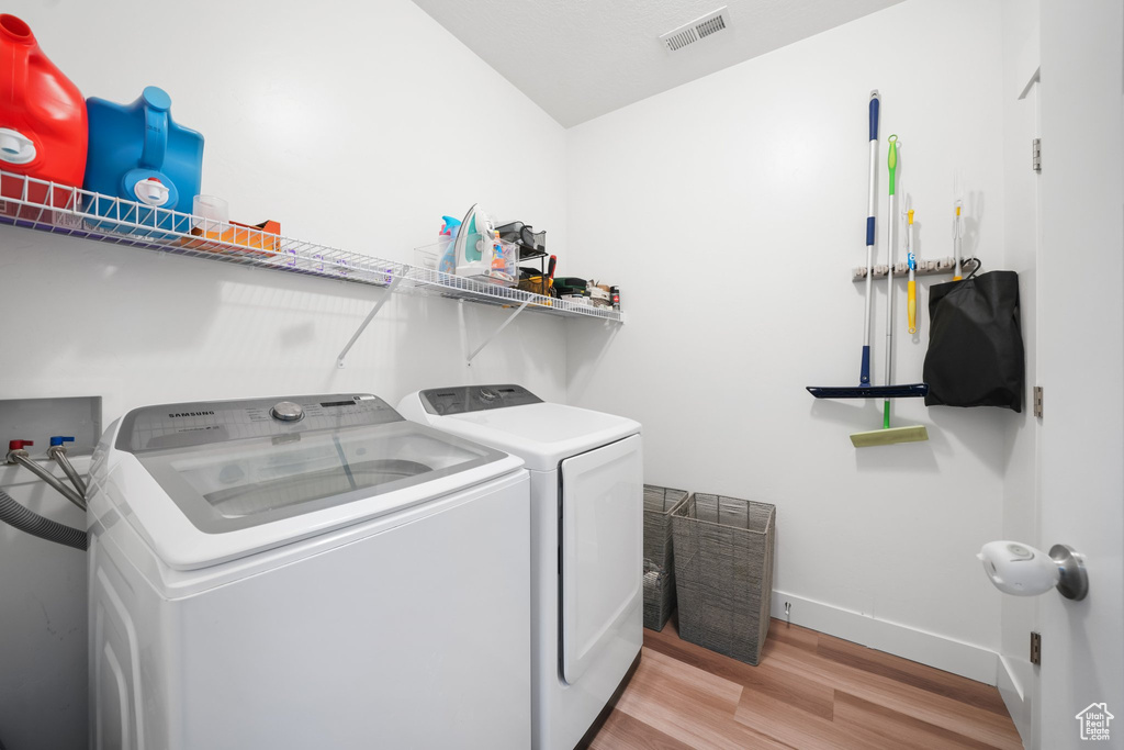 Clothes washing area with washer hookup, light hardwood / wood-style flooring, and washing machine and clothes dryer