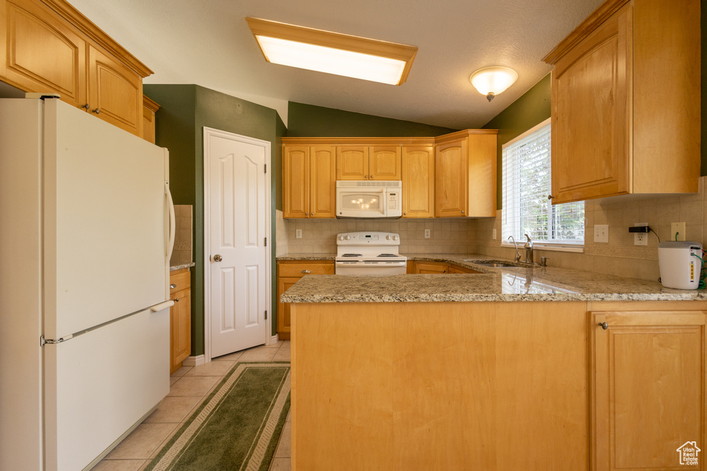 Kitchen with white appliances, tasteful backsplash, light stone counters, sink, and light tile floors