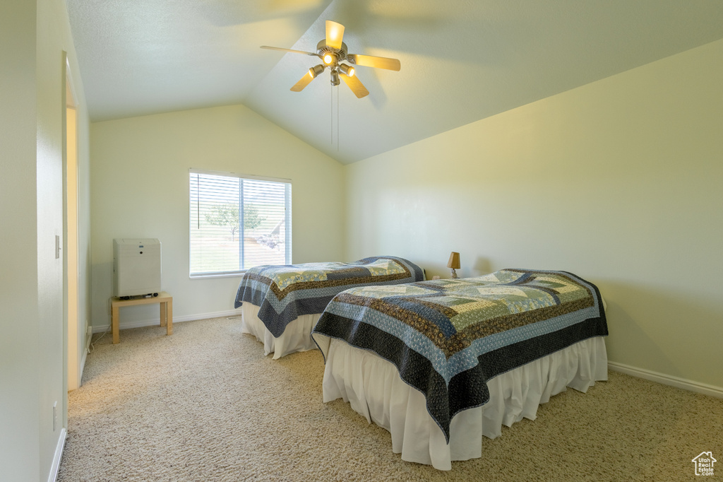 Bedroom with light colored carpet, ceiling fan, and vaulted ceiling