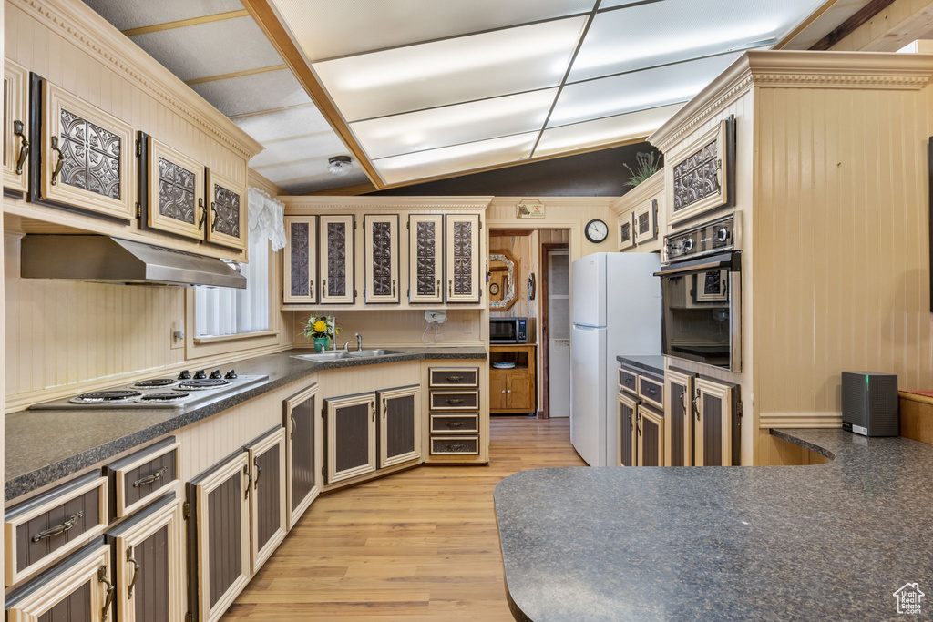 Kitchen with lofted ceiling, white appliances, sink, and light wood-type flooring