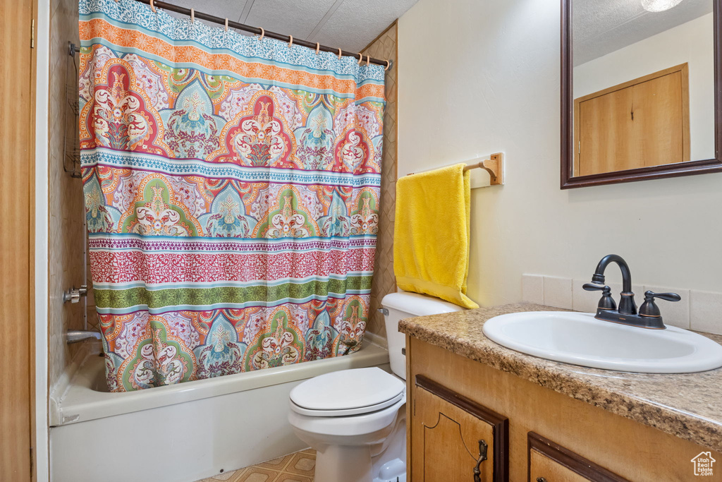 Full bathroom featuring toilet, tile flooring, shower / tub combo with curtain, a textured ceiling, and vanity