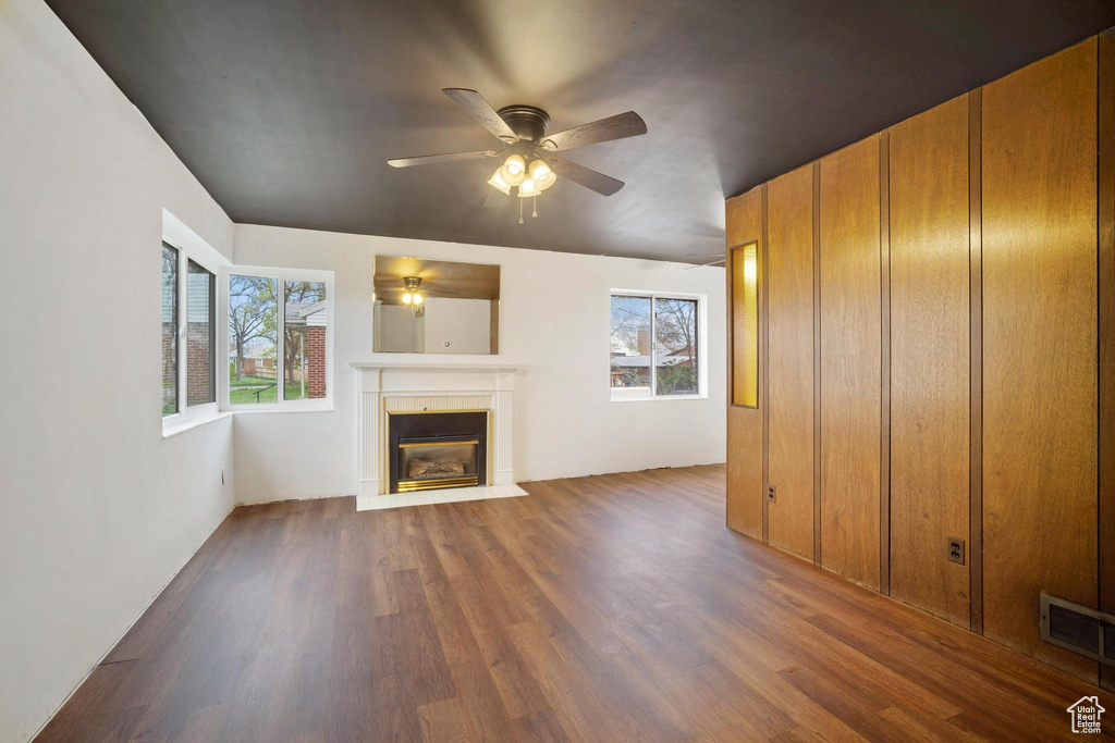 Unfurnished living room featuring a wealth of natural light, ceiling fan, and dark hardwood / wood-style floors