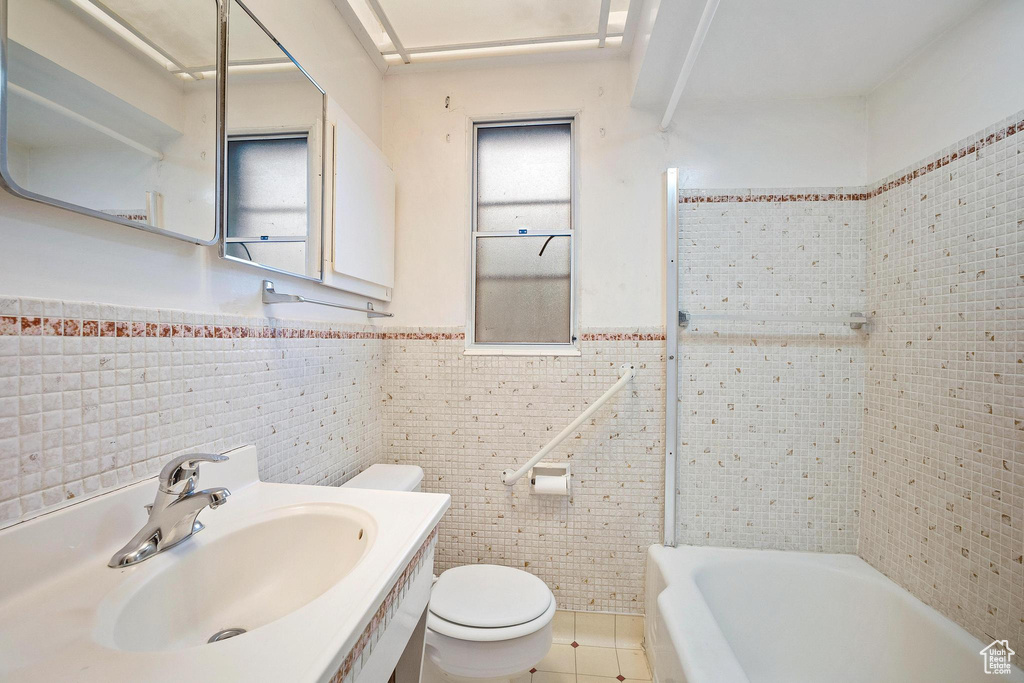 Full bathroom featuring tile walls, vanity, toilet, and tile flooring