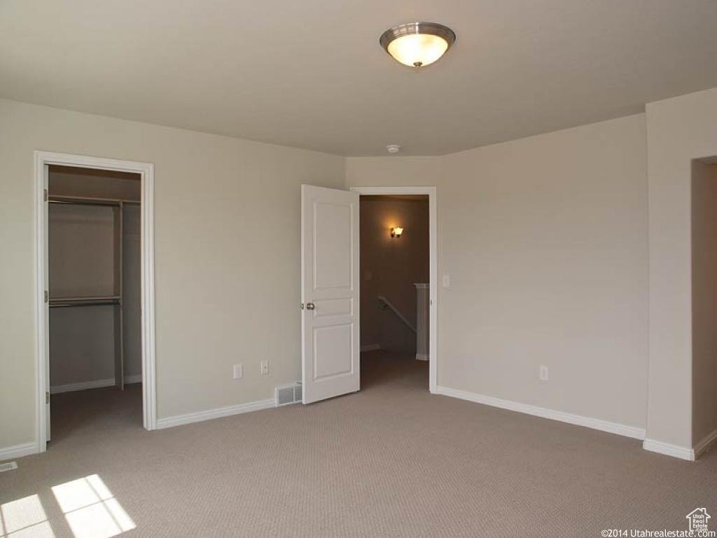 Unfurnished bedroom with light colored carpet, a spacious closet, and a closet