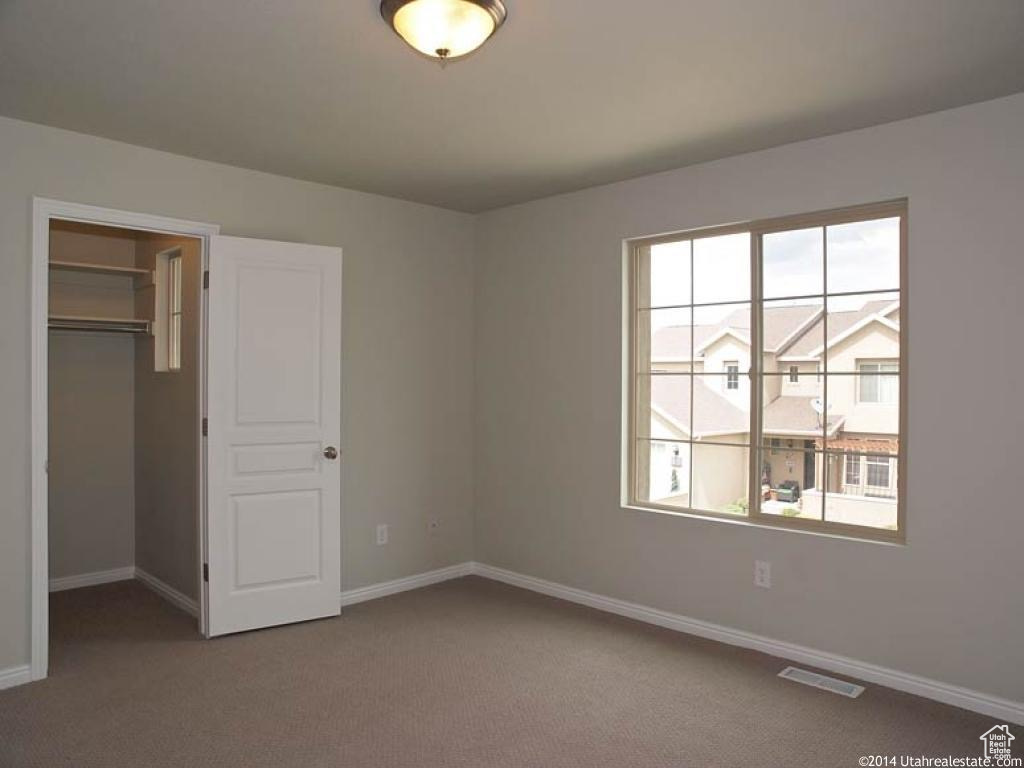 Unfurnished bedroom with a closet, multiple windows, and dark carpet