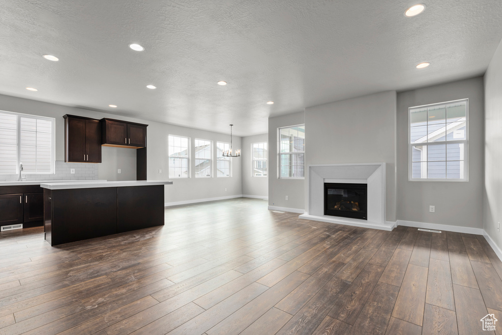Kitchen featuring dark brown cabinets, tasteful backsplash, hardwood / wood-style flooring, sink, and a center island