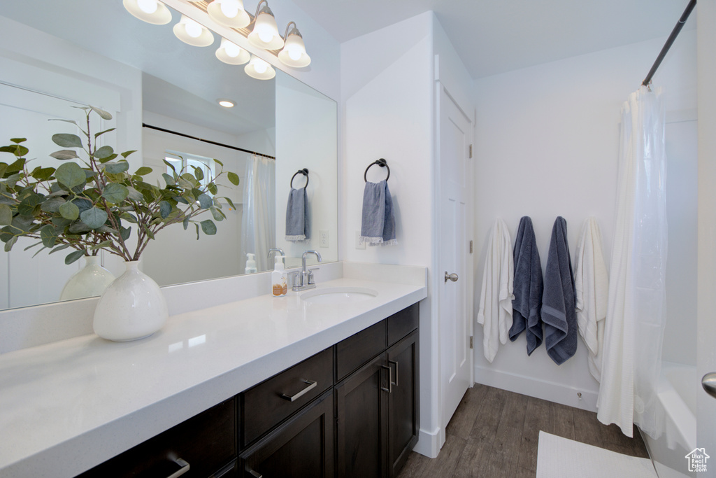 Bathroom with hardwood / wood-style floors, large vanity, and shower / bathtub combination with curtain