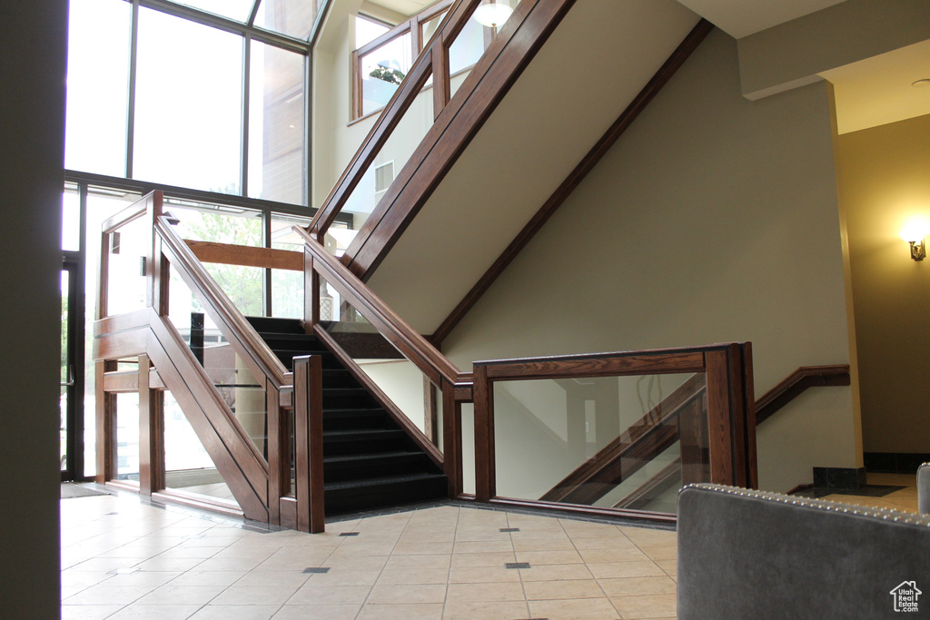 Stairway with a high ceiling and light tile flooring