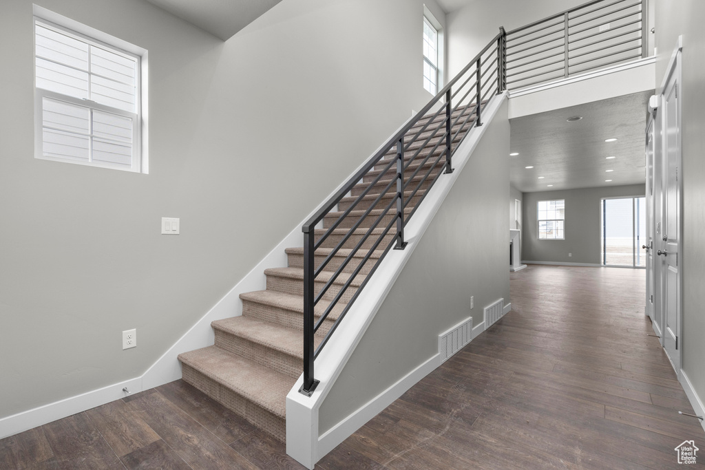 Stairway with a high ceiling and dark hardwood / wood-style floors