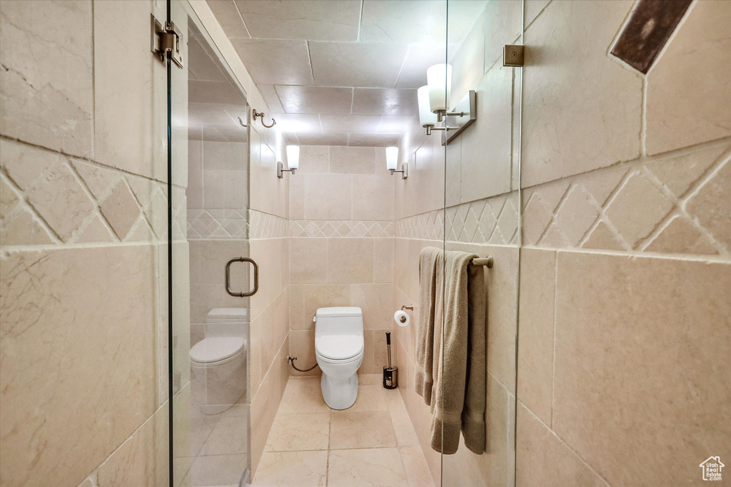 Bathroom featuring tile walls, tile floors, toilet, and walk in shower