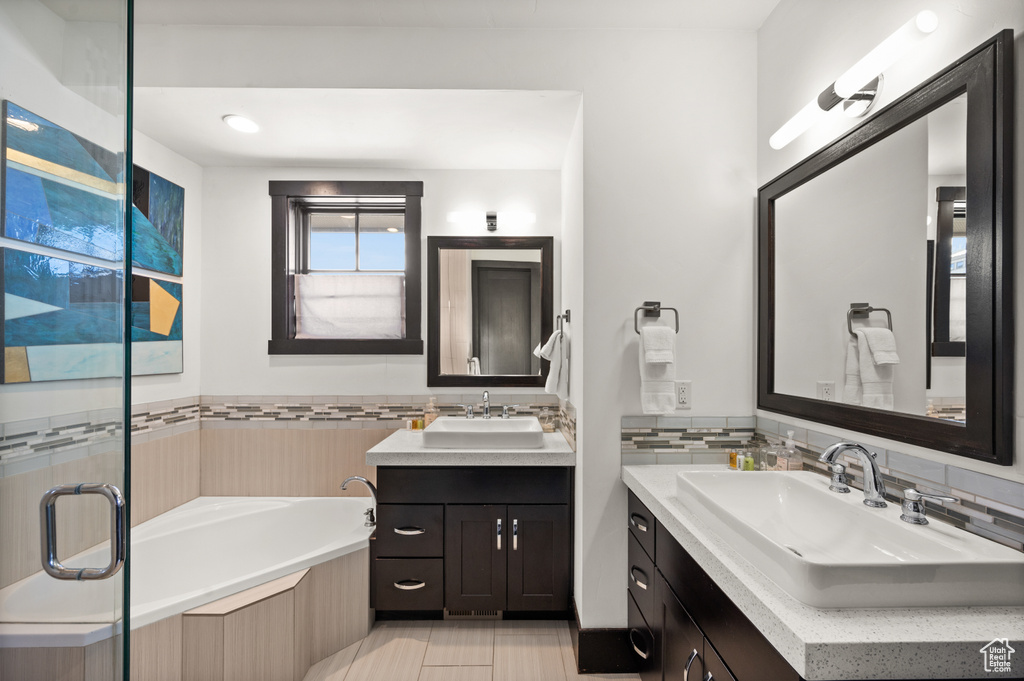 Bathroom featuring tasteful backsplash, tile floors, double vanity, and a bathtub
