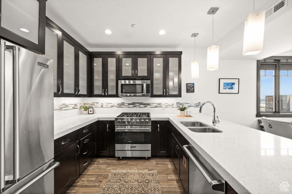 Kitchen featuring appliances with stainless steel finishes, dark hardwood / wood-style flooring, hanging light fixtures, and sink