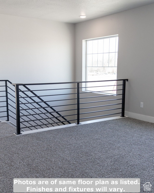 Stairway featuring a textured ceiling and carpet floors