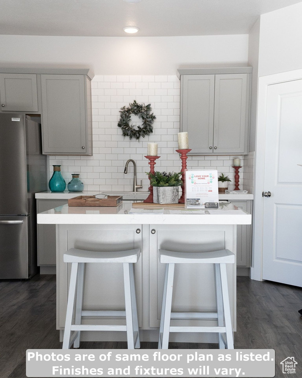 Kitchen featuring stainless steel refrigerator, dark wood-type flooring, and backsplash