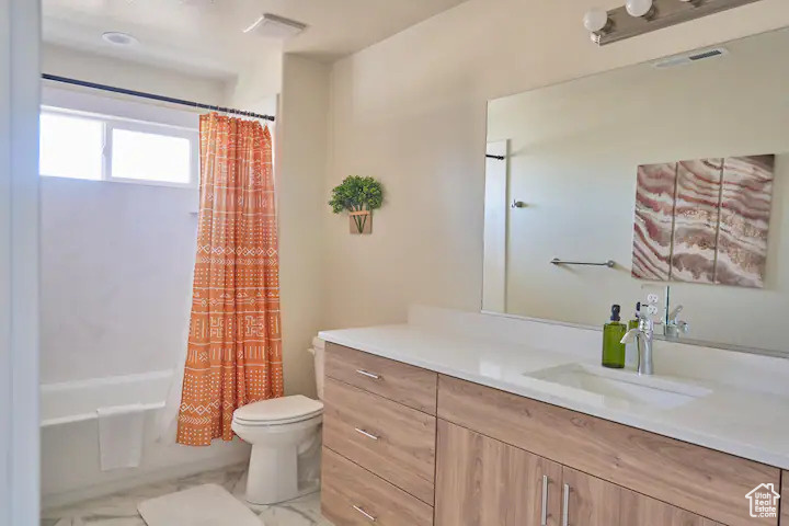 Full bathroom with tile floors, vanity, shower / tub combo, and toilet