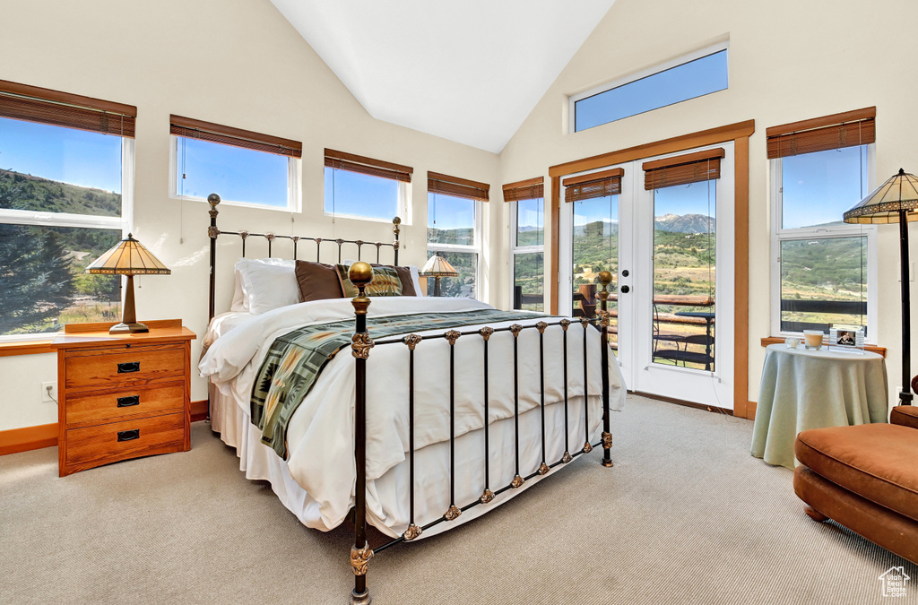 Bedroom featuring high vaulted ceiling, light carpet, access to outside, and multiple windows