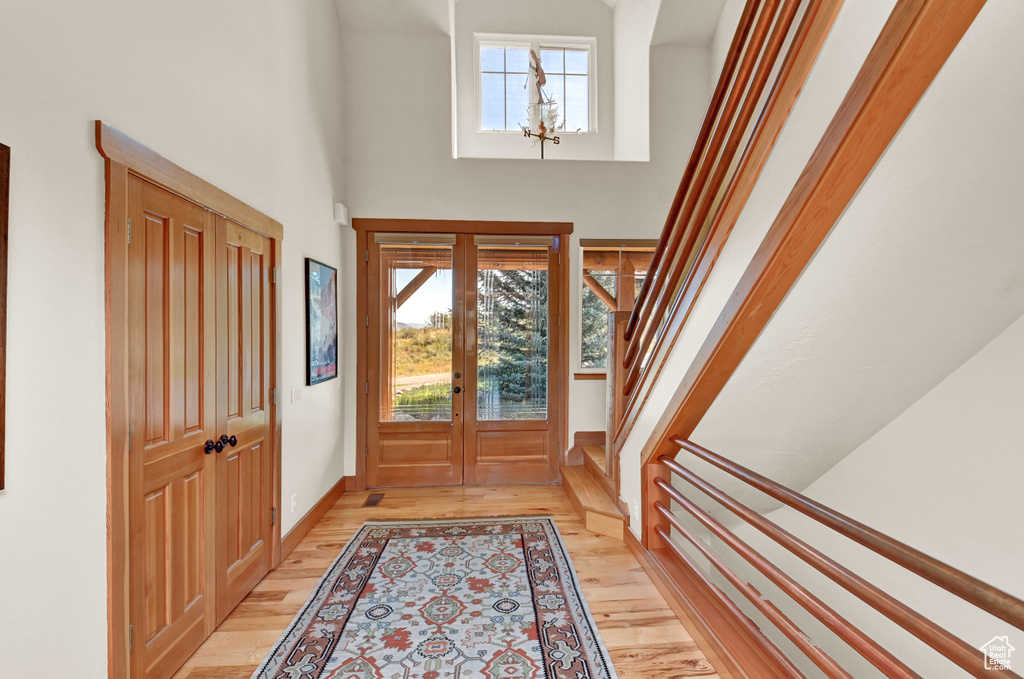 Foyer featuring french doors, light hardwood / wood-style flooring, and a high ceiling