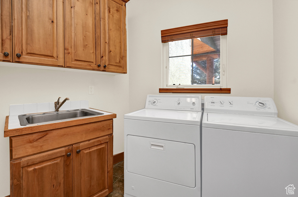 Laundry room featuring cabinets, sink, separate washer and dryer, and dark tile flooring